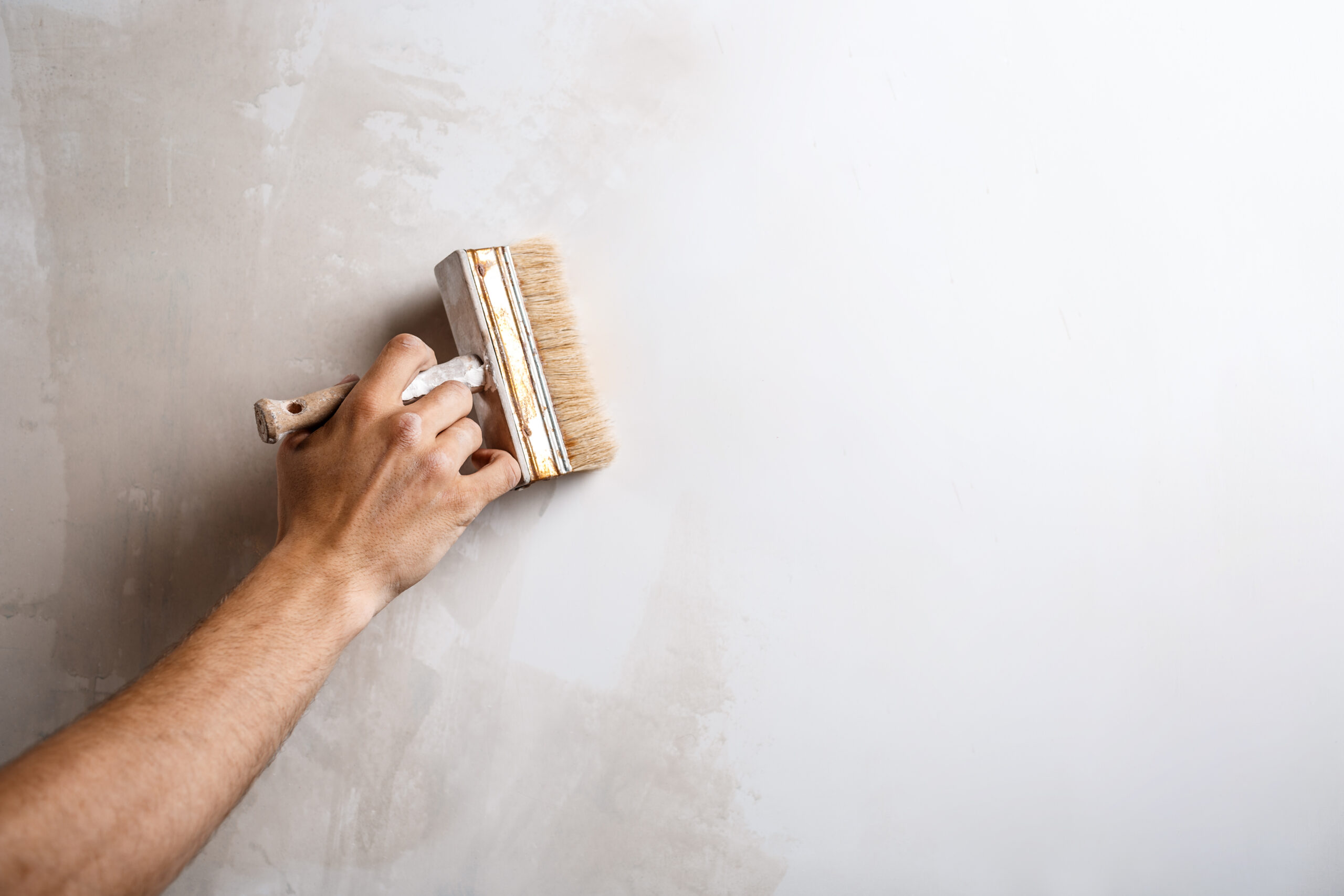 Close up of hand painting wall with brush. Copy space.